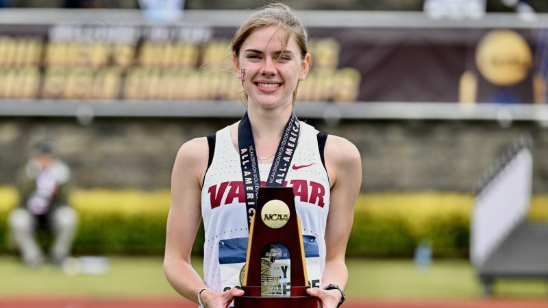Smiling athlete wearing a medal and holding a trophy.