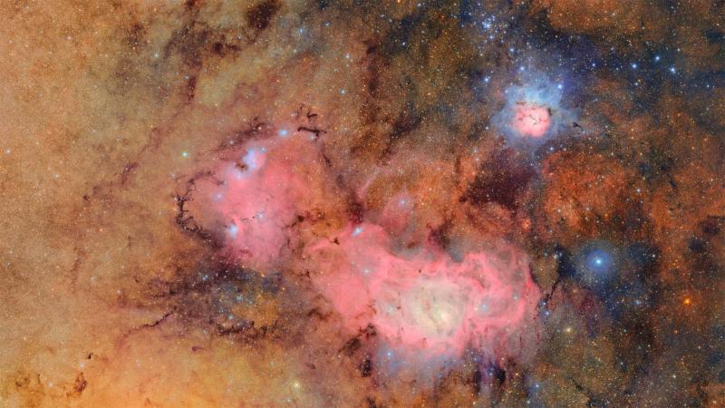 Orange and pink colors of the Trifid and Lagoon nebulas. Clouds of hydrogen emit a pink glow while hot stars shine blue.