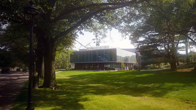 Exterior photo of a building surrounded by large trees and a grass lawn.