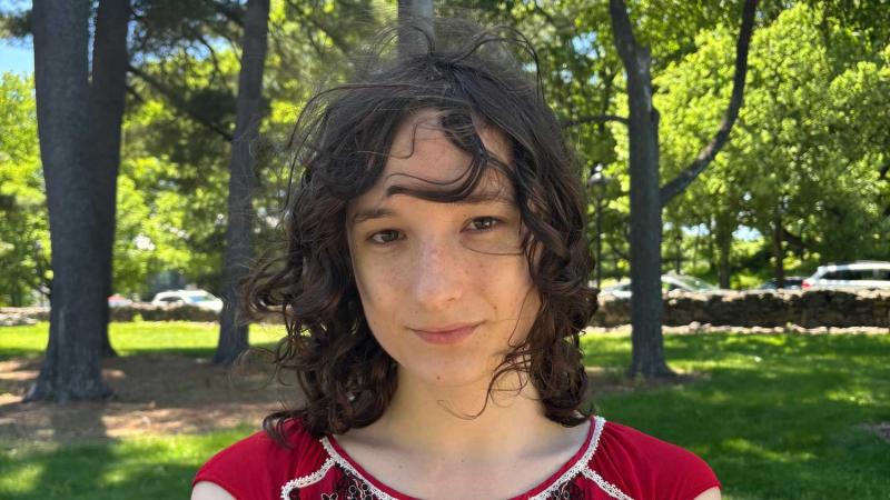 Headshot of a smiling person outdoors.