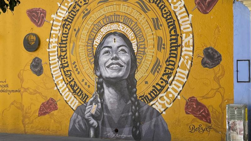 A golden colored mural depicting a young smiling woman.