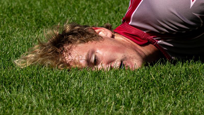A rugby player lying face first in the grass.