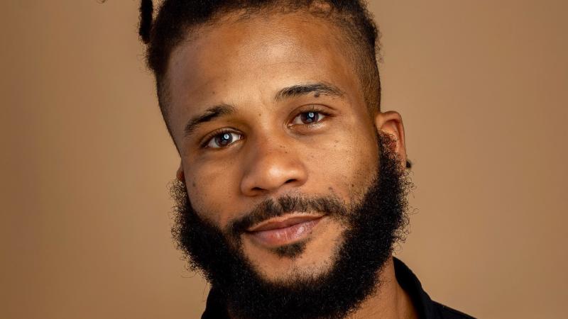A photo of Winston Dynamite Brown, a person with black hair and a black shirt.