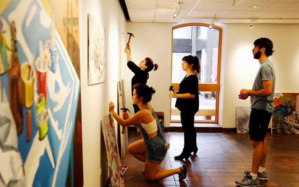 Students putting up artwork in a gallery
