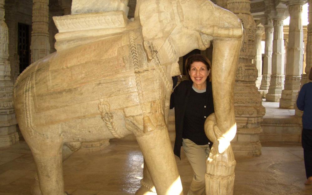Susan Yacubian Klein ’64 standing beneath the trunk of a stone carved elephant