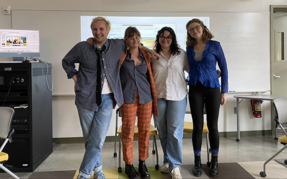 Four students in front of a projection screen