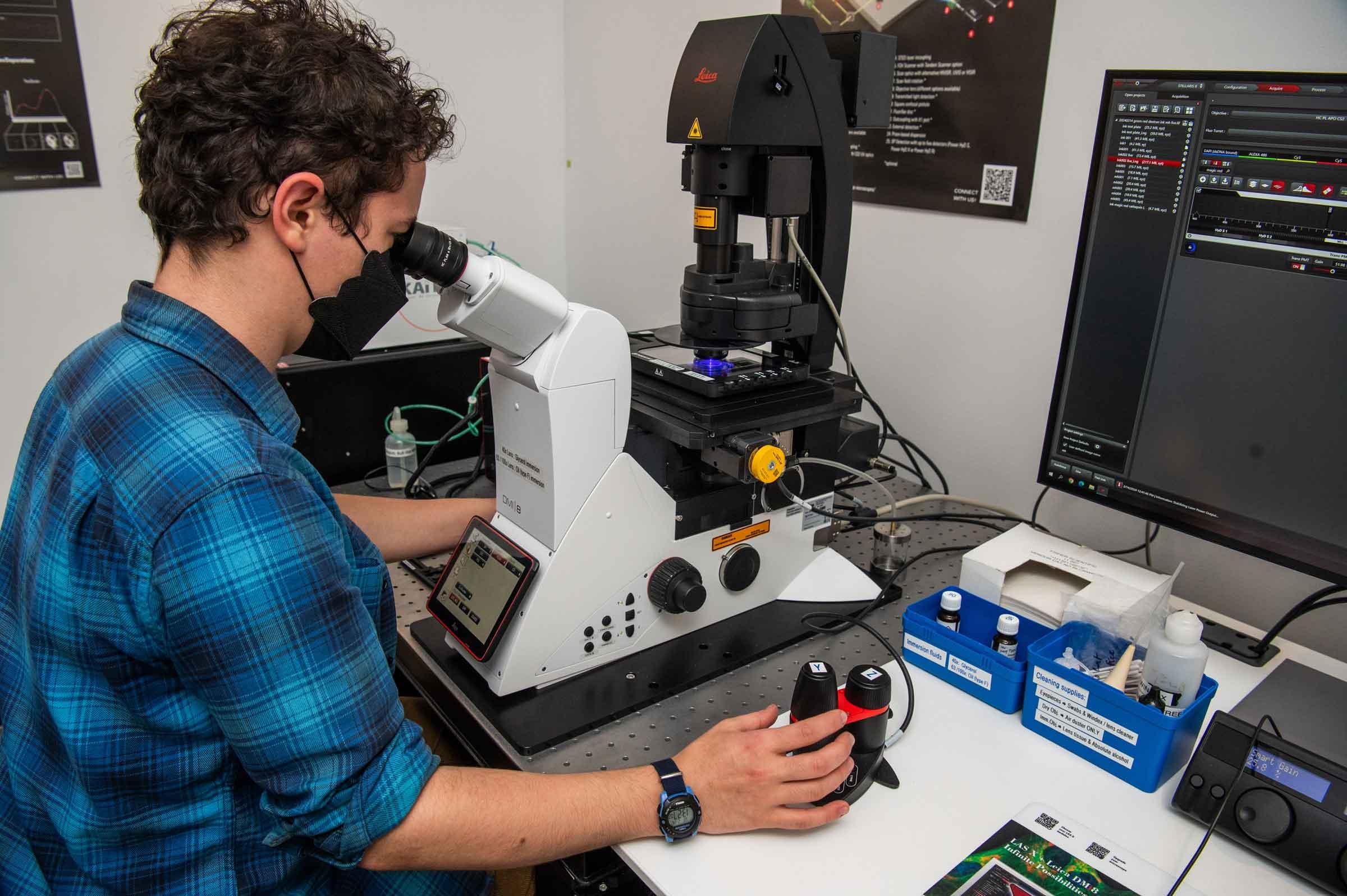 Person looking into a microscope at a desk.