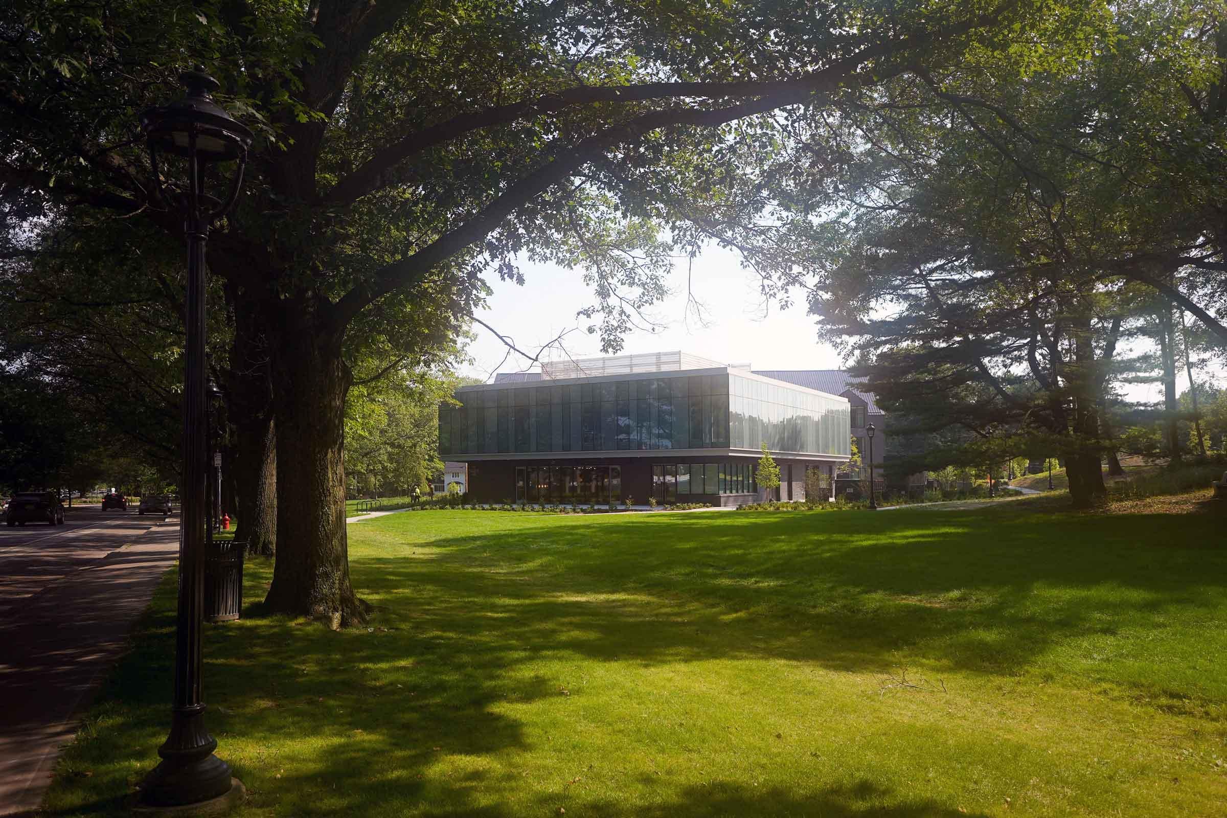 Exterior photo of a building surrounded by large trees and a grass lawn.