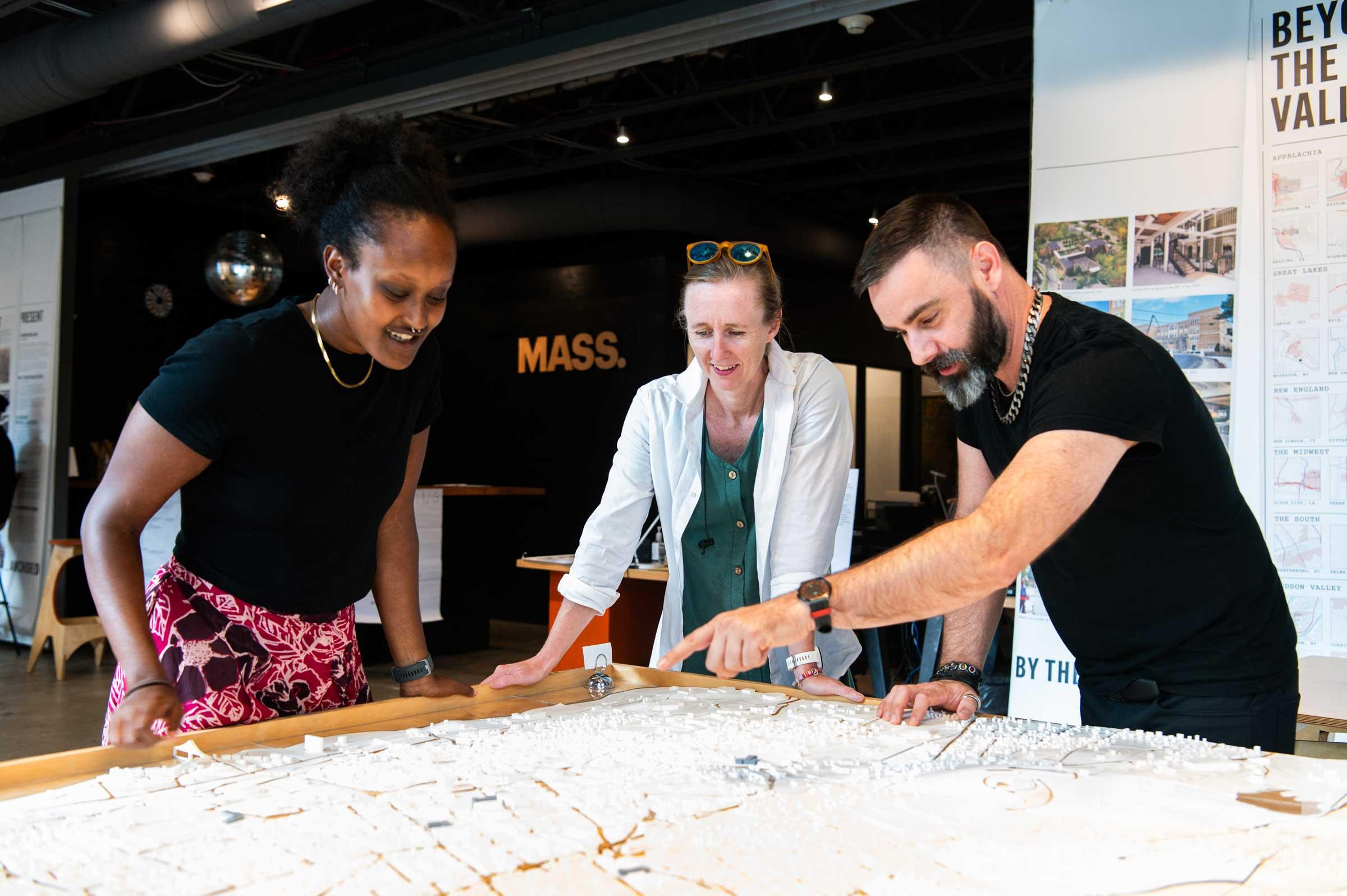 Three people looking over a map while one of the people points something out.