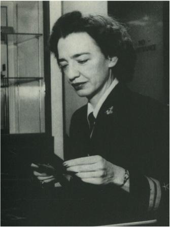 Old black and white photo of Professor (and later Rear Admiral) Grace Murray Hopper VC Class of 1928 Ph.f7.14 wearing a uniform and holding and looking at a photo. 