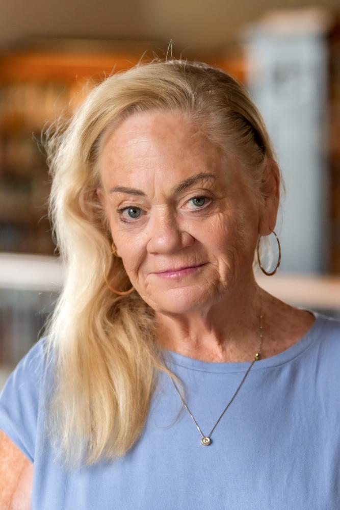 Portrait of a person with library shelves in the background.