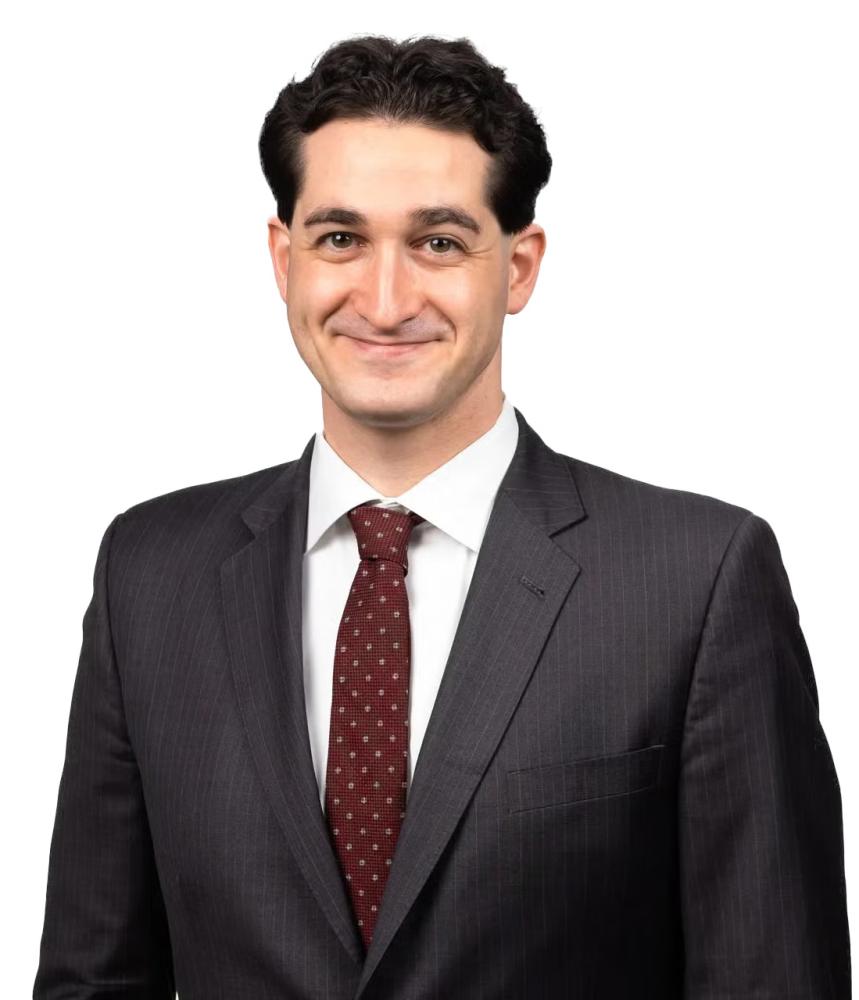 Brian Farkas wearing a charcoal grey pinstripe suit and a maroon patterned tie against a white background.