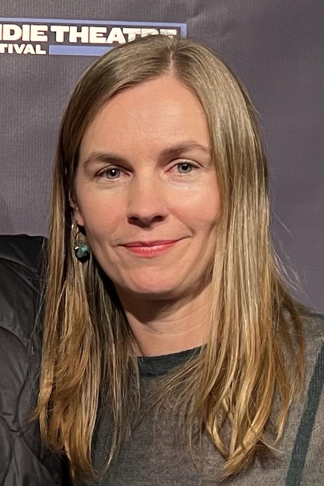 Close-up portrait of a person with long blond hair smiling at the camera.