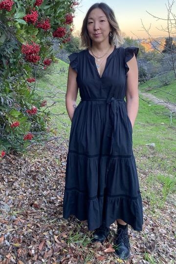 Author Katherine Yungmee Kim ’93, wearing a long blue dress, stands by a tree. 