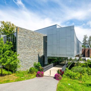 Bridge for Laboratory Sciences at Vassar College, a large glass and brick classroom building surrounded by trees and flowers..