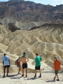 People standing with back to camera in a desert mountainous landscape.