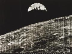 A monochrome photo of the lunar surface, showing the Earth in the background.