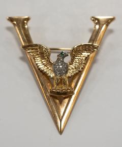 Picture of a gold pin/broach with a diamond studded eagle sitting on top of a "V"