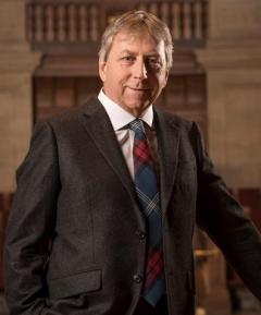 Dr. Peter Mathieson, Principal and Vice Chancellor of the University of Edinburgh wearing a brown suit, white shirt and red and blue patterned tie 