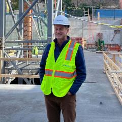 Andrew Commers at a construction site wearing neon yellow vest and hard hat