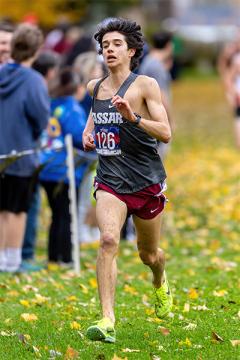Miles Takiguchi runs through a field covered with fallen autumn leaves