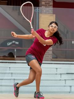 Action shot of Sehar Dey-Kohli ’24 raising her racket to hit the ball on the squash court.