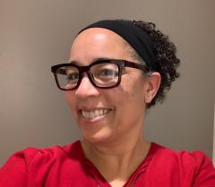 Person wearing a red shirt, black eyeglasses and has short dark hair.