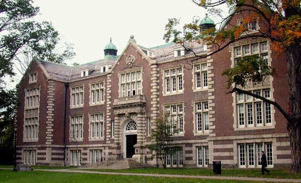 Exterior photo of Rockefeller Hall - a red brick building with tan accent with some trees around the building.bricks and trim, a dark colored roof, and 2 green turrets 