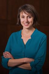 Alison Spodek Keimowitz wearing an aqua colored shirt against a brown background.