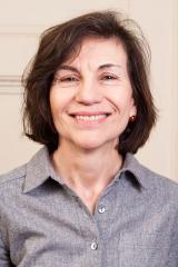 Eve D’Ambra wearing a gray collared shirt against a light background.