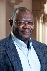 Ismail O. D. Rashid wearing a light blue collared shirt and blue jacket against a light background.