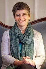 Margaret L. Ronsheim wearing a light colored shirt and green scarf against a light background.