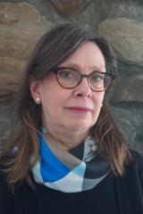 Pictured: Yvonne Elet - A white woman with glasses in front of stone wall.