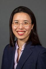 Portrait of a woman with glasses and a blue blazer smiling