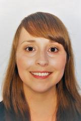 Woman with shoulder-length copper brown hair in front of a white backdrop smiling for the camera.