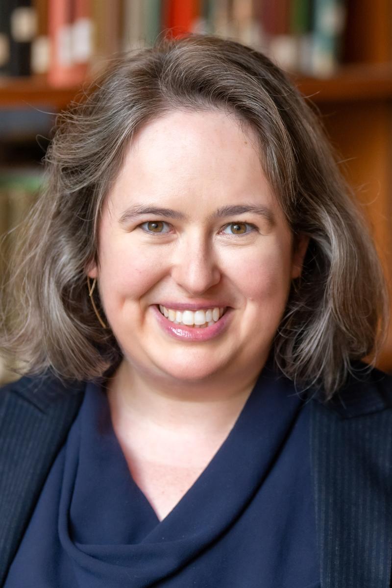 Portrait of a person with library book shelves in the background.