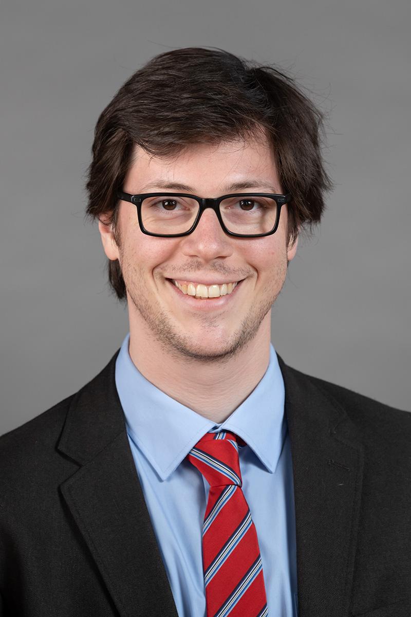 Portrait of a person with a suit, tie, and glasses.