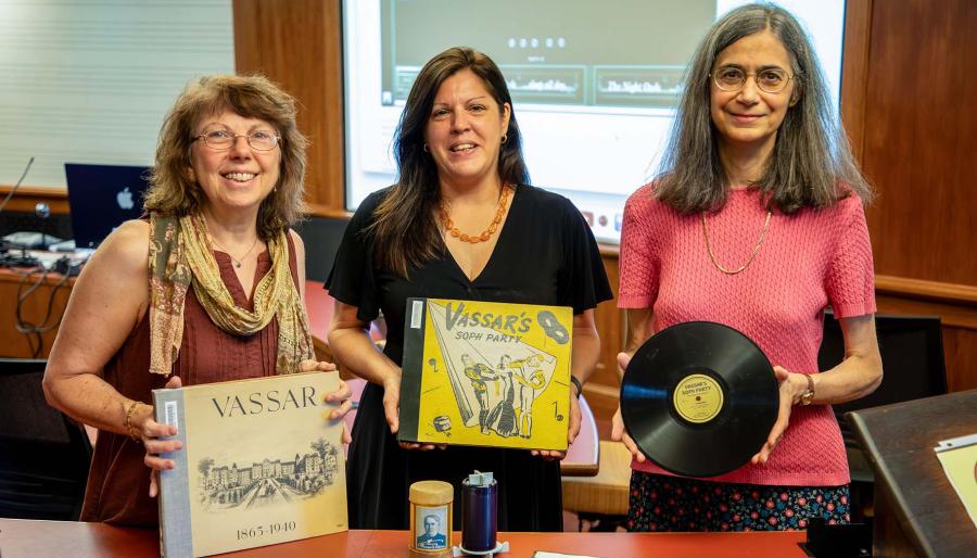 Three women, one holding a record, the other two holding old record album books 