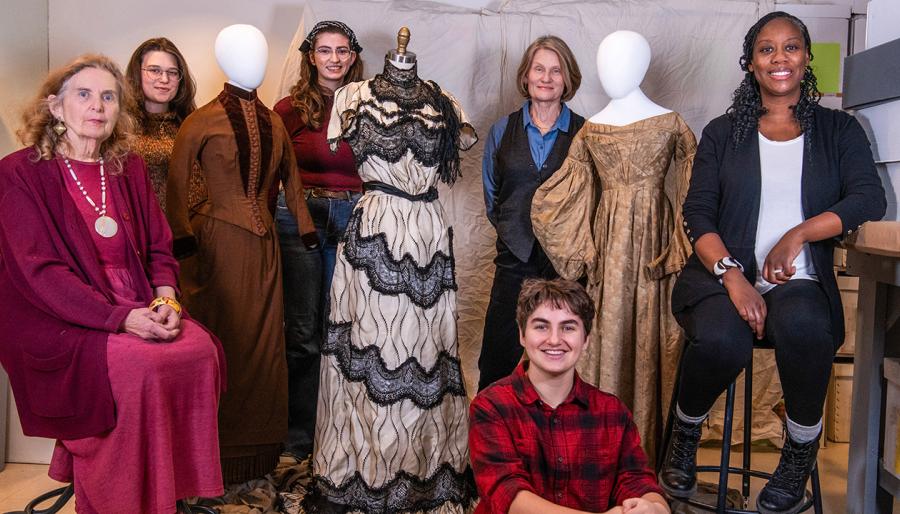 A group standing among a few mannequins adorned with dresses.