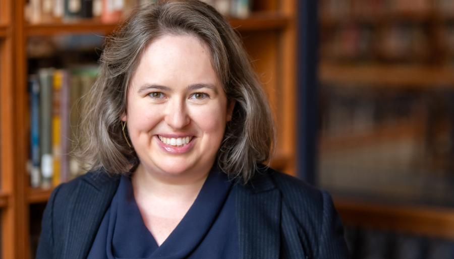 Portrait of a person with library book shelves in the background.