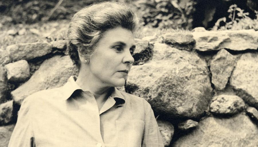 A person in profile leaning against a wall of rock.