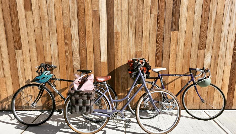 A series of bikes lines up against a wooden-slatted wall.