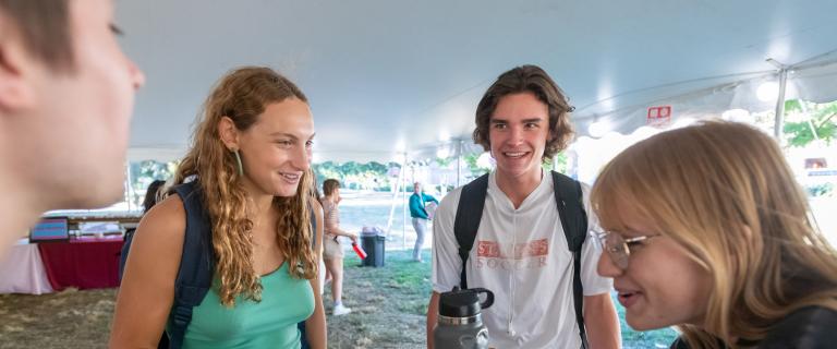 A couple of students laughing under white tent at Vassar College Convocation.