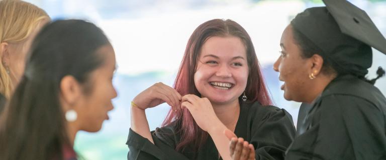 Female students laughing wearing black gowns at Vassar College Convocation.