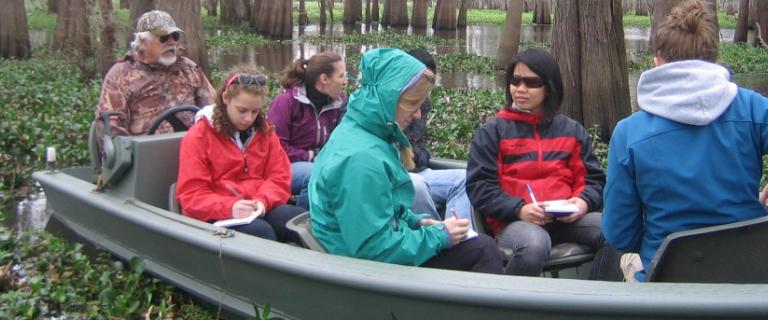 Students sitting in a boat through going through the Atchafalaya Swamp in Louisiana