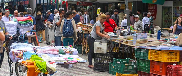 People in a downtown market on the street with books an other items.  Rio de Janeiro
