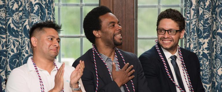 Three people sitting in front of a window smiling and clapping.