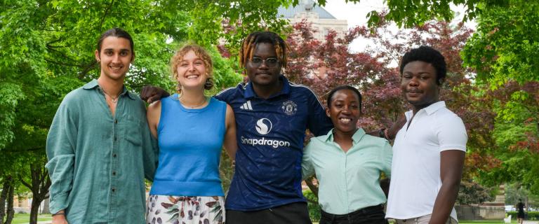 A group standing together smiling, with trees in the background.