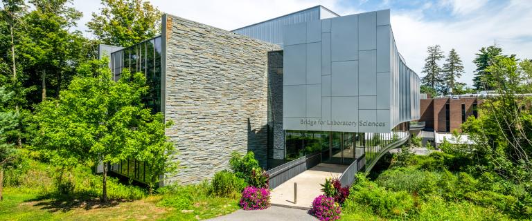 Bridge for Laboratory Sciences at Vassar College, a large glass and brick classroom building surrounded by trees and flowers..