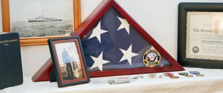 Shelf with mementos including a folded American flag in a frame.